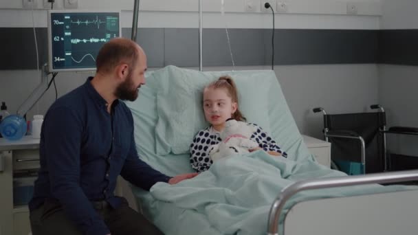 Beteg lány gyermek fekszik az ágyban megvitatása aggódó apa a diagnózis konzultáció során — Stock videók