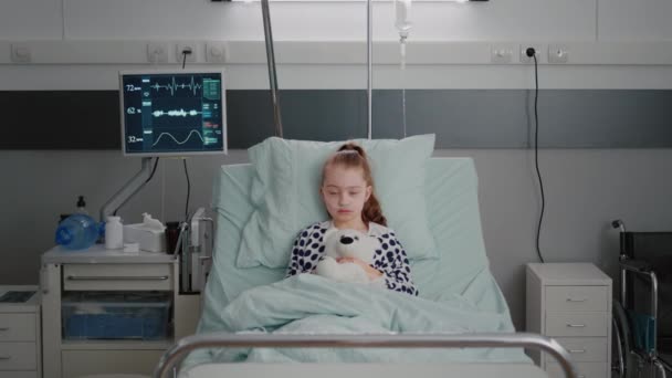 Portrét hospitalizované nemocné dívky dětské pacientky držící medvídka odpočívající v posteli během lékařské konzultace — Stock video