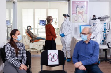 Stomatoloji kliniğindeki yaşlı kadın dişçiyle konuşuyor.
