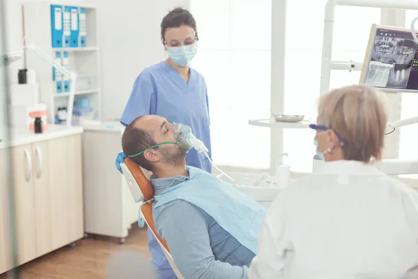 Assistente do hospital colocando máscara de oxigênio antes da cirurgia dentária — Fotografia de Stock