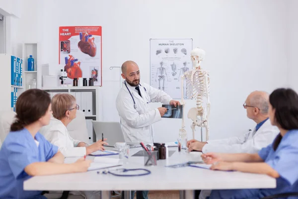 L'équipe de l'hôpital discute de la structure osseuse en utilisant la radiographie médicale expliquant le diagnostic de maladie — Photo