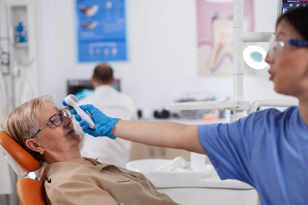 Помощник стоматолога держит цифровой индикатор температуры тела — стоковое фото