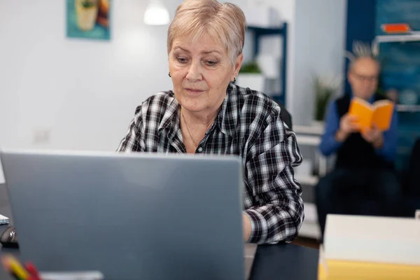Старша леді працює і вказує на екран комп'ютера — стокове фото