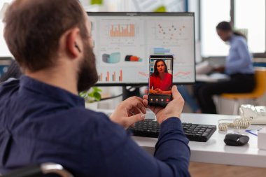 Tekerlekli sandalyede oturan felçli yönetici video görüşmesi için akıllı telefon tutuyor.