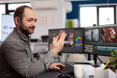 Video düzenleyici elinde akıllı telefon tutarak konuşuyor