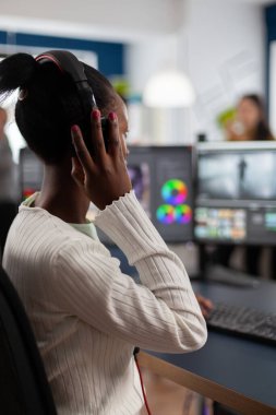 Siyah video düzenleyici iki monitörle bilgisayar üzerinde çalışıyor