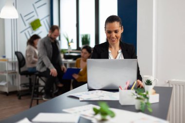 Dizüstü bilgisayarda yazı yazan mutlu İspanyol kadın masada oturuyor.