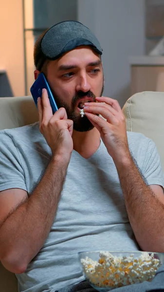 Cansado homem com máscara de sono colocar falando no smartphone — Fotografia de Stock