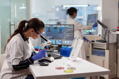 Biyoteknoloji bilimcisi mikroskopla genetik materyali analiz ediyor.