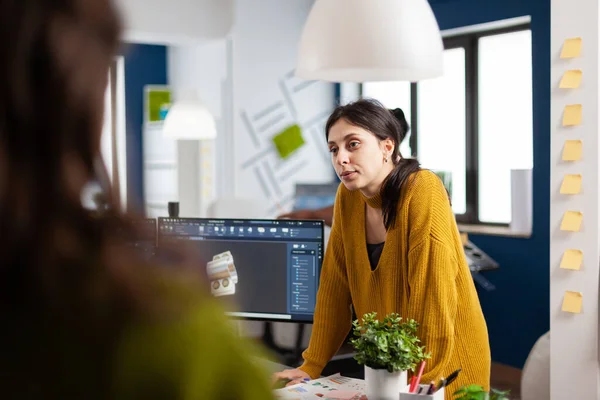 Mujer diseñadora industrial discutiendo con colega de pie en el escritorio —  Fotos de Stock