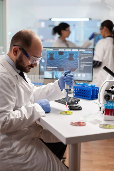 Cientista fazendo experimento genético usando amostra de sangue em micropipeta — Fotografia de Stock