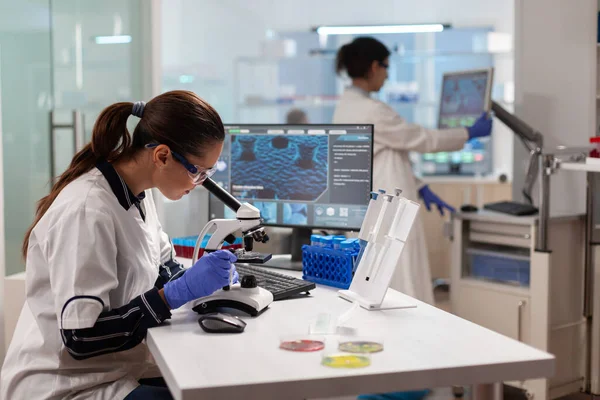 Científico de biotecnología mirando a través del microscopio analizando material genético —  Fotos de Stock