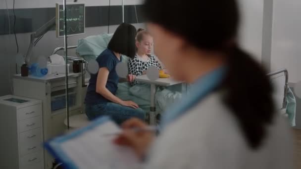 Kranker Kinderpatient sitzt mit Sauerstoff-Nasenschlauch im Bett und isst während des Mittagessens gesunde Nahrung — Stockvideo