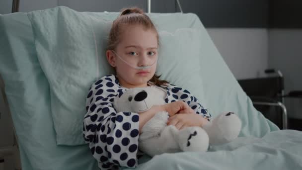 Porträtt av liten flicka patient bär syre nasal röret vilar i sängen återhämtning — Stockvideo