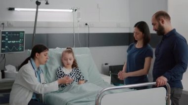 Pratisyen kadın doktor küçük çocuk hasta parmağına oksimetre takıyor.