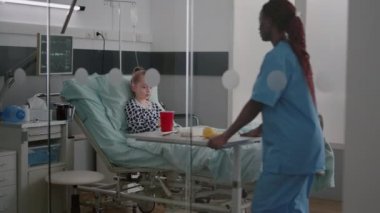 Afrikalı Amerikalı hemşire hasta hastaya sağlıklı beslenme yemeği getiriyor.