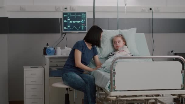 Mãe preocupada sentada ao lado da filha doente durante exame de doença na enfermaria do hospital — Vídeo de Stock