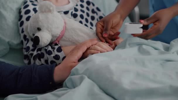 Крупный план черной медсестры, ставящей медицинский оксиметр на больной палец ребенка, анализирующий пульс сердцебиения — стоковое видео