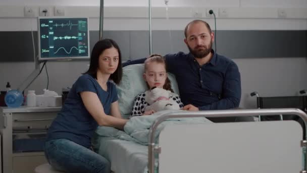 Portrait of sad family looking into camera while holding sick daughter hands — Stock Video