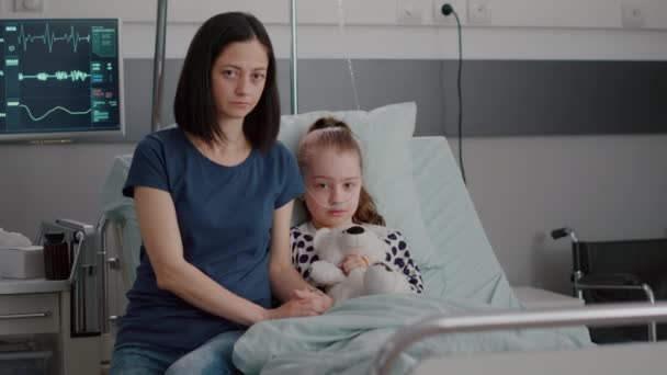 Portrait of worried mother sittting beside hospitalized little child looking into camera — Stock Video