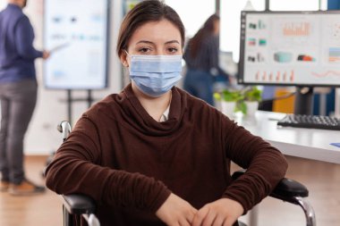 Woman employee with disabilities with protection mask looking at camera clipart