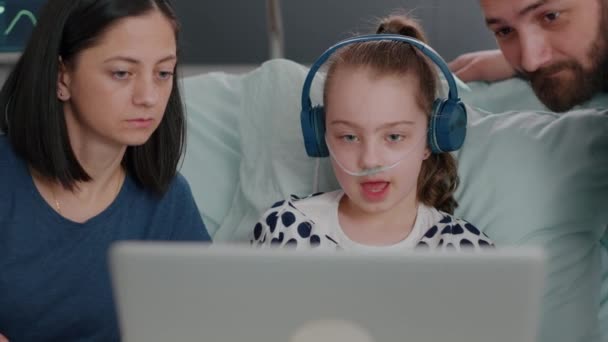 Family sitting beside daughter while playing online videogames using laptop computer in hospital ward — Stock Video