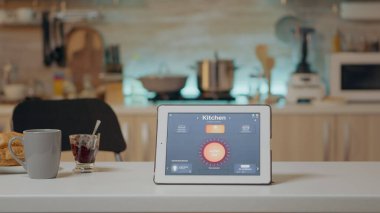 Akıllı yazılımlı tablet mutfaktaki masaya yerleştirilmiş ve kimse yok.
