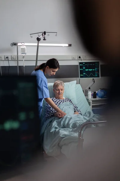 Freundlicher Arzt beruhigt kranken alten Patienten beim Händchenhalten — Stockfoto