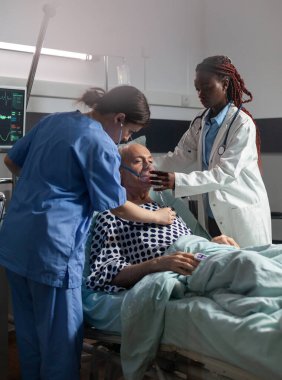 Afrikalı doktor, yaşlı hastaya solunum tüpü kullanarak nefes almasında yardım ediyor.