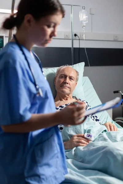 Medical nurse in scrubs taking notest on cliboard