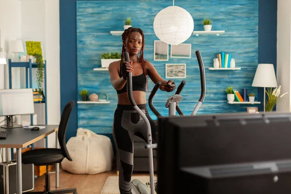 Africano apto mulher forte fazendo exercício cardio na máquina elíptica — Fotografia de Stock