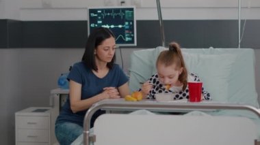 Anne hasta kızıyla ayakta duruyor ve öğle yemeğinde sağlıklı yemek yiyor.