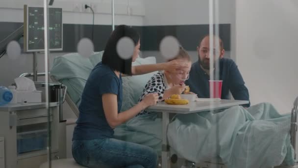 Famille assise avec une petite fille malade tout en mangeant des aliments sains pendant l'examen de récupération — Video