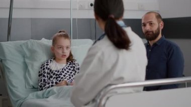 Pediyatrist doktor hasta hasta ve babasıyla hastalık tedavisini tartışıyor