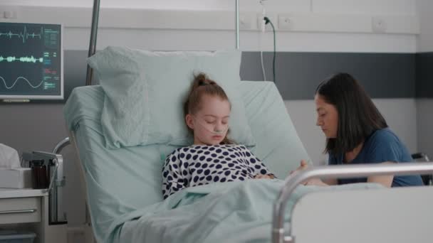 Aggódó anya ül a kislány mellett, imádkozik, miközben alszik a műtét után. — Stock videók