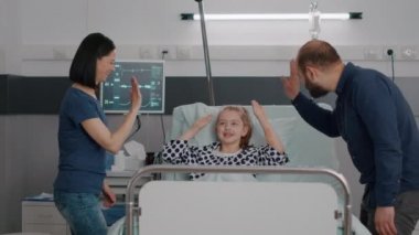 Mutlu aile, klinik terapisinden sonra iyileşen küçük kıza beşlik çakıyor.