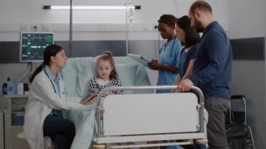 Afro-Amerikan hemşire serum torbasını kontrol ederken doktor hastalık belirtilerini izliyor.