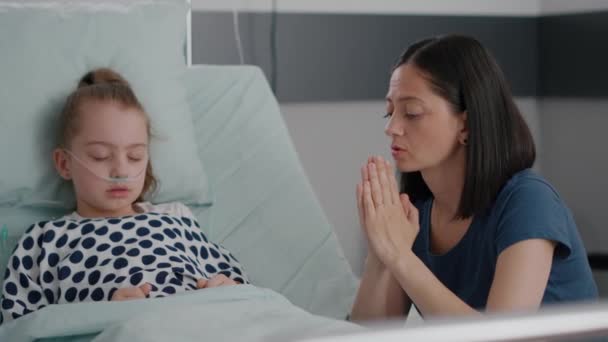 Sick daughter sleeping after health care surgery while worried mother praying for sickness treatment — Stock Video