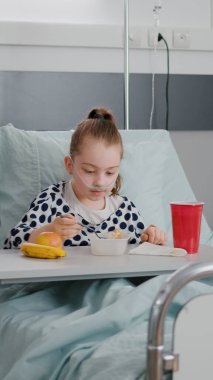 Annem hasta bir kızla ayakta duruyor ve öğle yemeğinde sağlıklı yemekler yiyor. Tıbbi uzmanlık bekliyor.