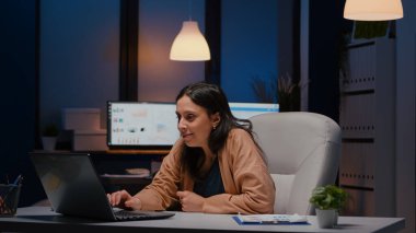 Dizüstü bilgisayara bakarken gülümseyen neşeli iş kadını