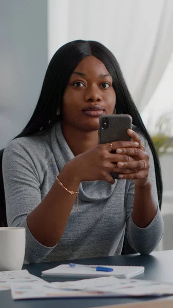 Estudiante negro sosteniendo el teléfono en las manos charlando con la gente buscando información de comunicación — Foto de Stock