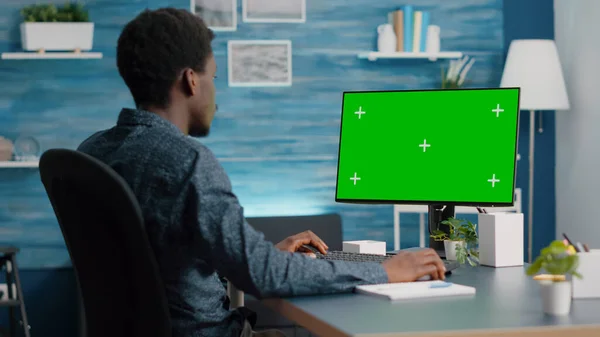 Hombre afroamericano usando y escribiendo en la computadora maqueta con pantalla verde — Foto de Stock