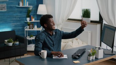 Otantik Afro-Amerikan siyahi adam sıcak oturma odasında selfie çekiyor.