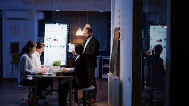 Şirketin toplantı odasında fazla mesai yaparken sinirli iş adamı bağırıyor.