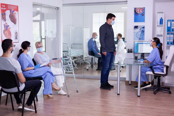 Asistente y mujer discapacitada con marco para caminar hablando en la sala de espera — Foto de Stock