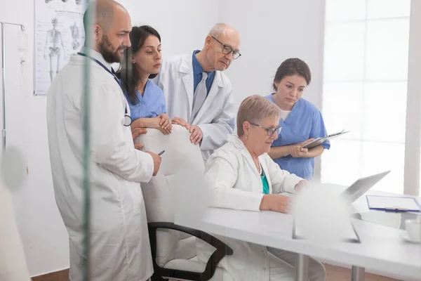 Especialistas médicos trabajo en equipo mirando computadora portátil examinando la tomografía de enfermedades — Foto de Stock