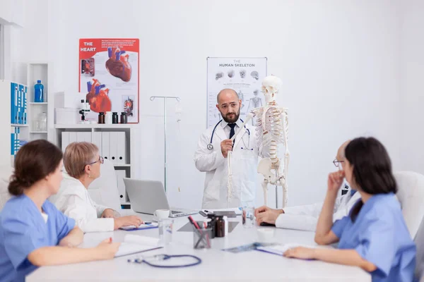 Artsen met stethoscoop die handbot vasthouden en het menselijk skelet verklaren — Stockfoto
