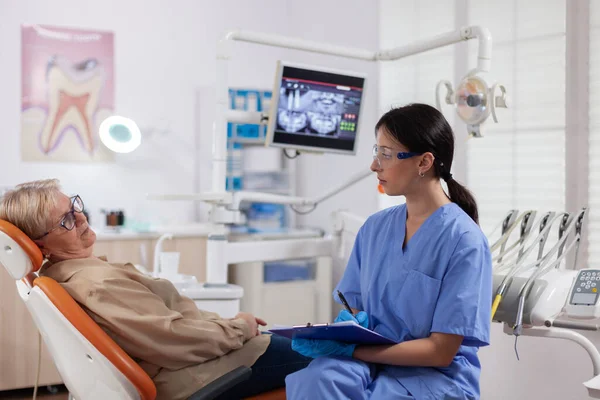 Tandheelkundige assistent neemt notities op klembord in tandarts kliniek — Stockfoto