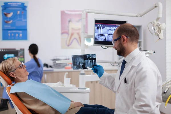 Dentysta asystent daje doktorowi rentgen starszej kobiety — Zdjęcie stockowe