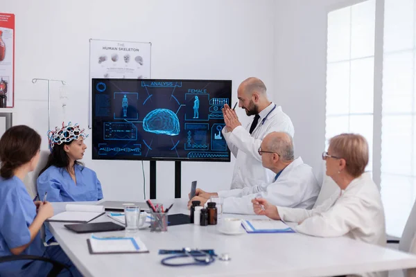 뇌 질환을 분석하는 의사들에게 디지털 방사선 촬영을 보여 주는 신경 학자 — 스톡 사진